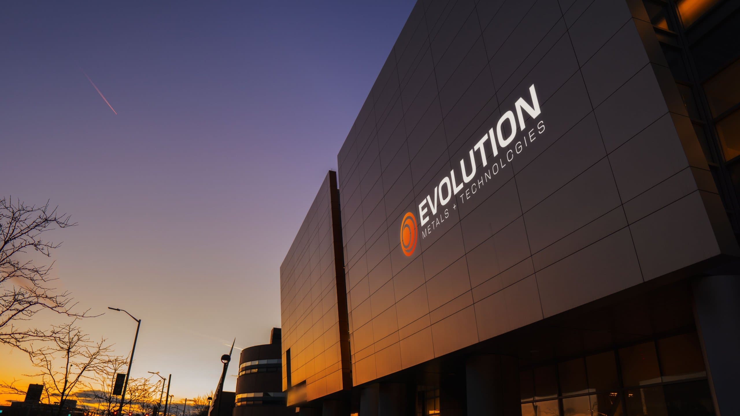 Modern facility with the Evolution Metals & Technologies logo at dusk